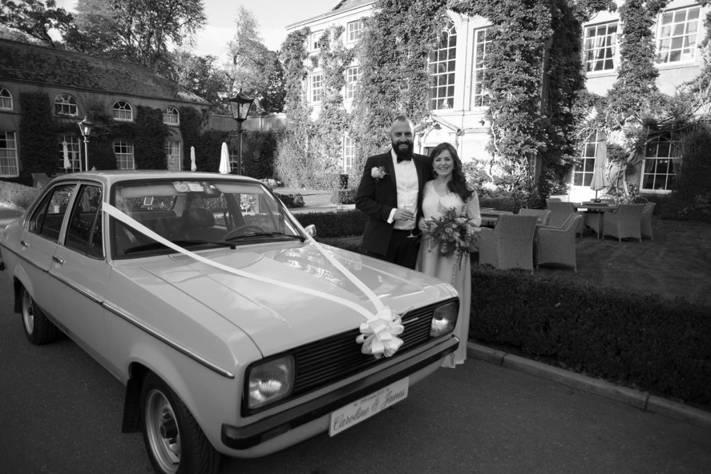 Mount Juliet Estate Wedding - wedding couple getting into vintage car with wedding decorations on it