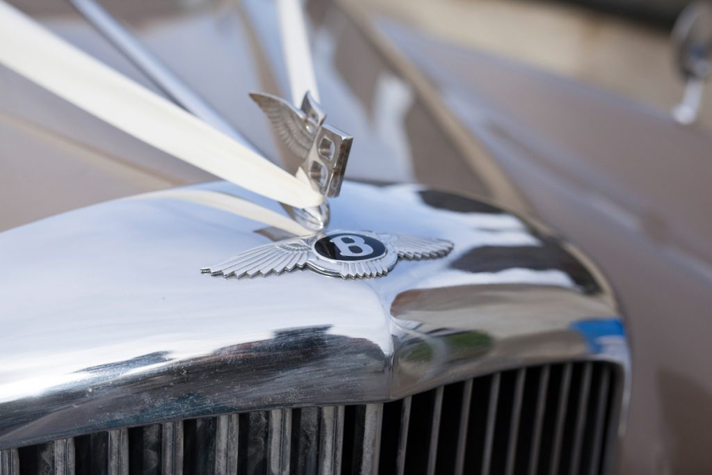 Close-up picture of the emblem on the front of a Bentley car