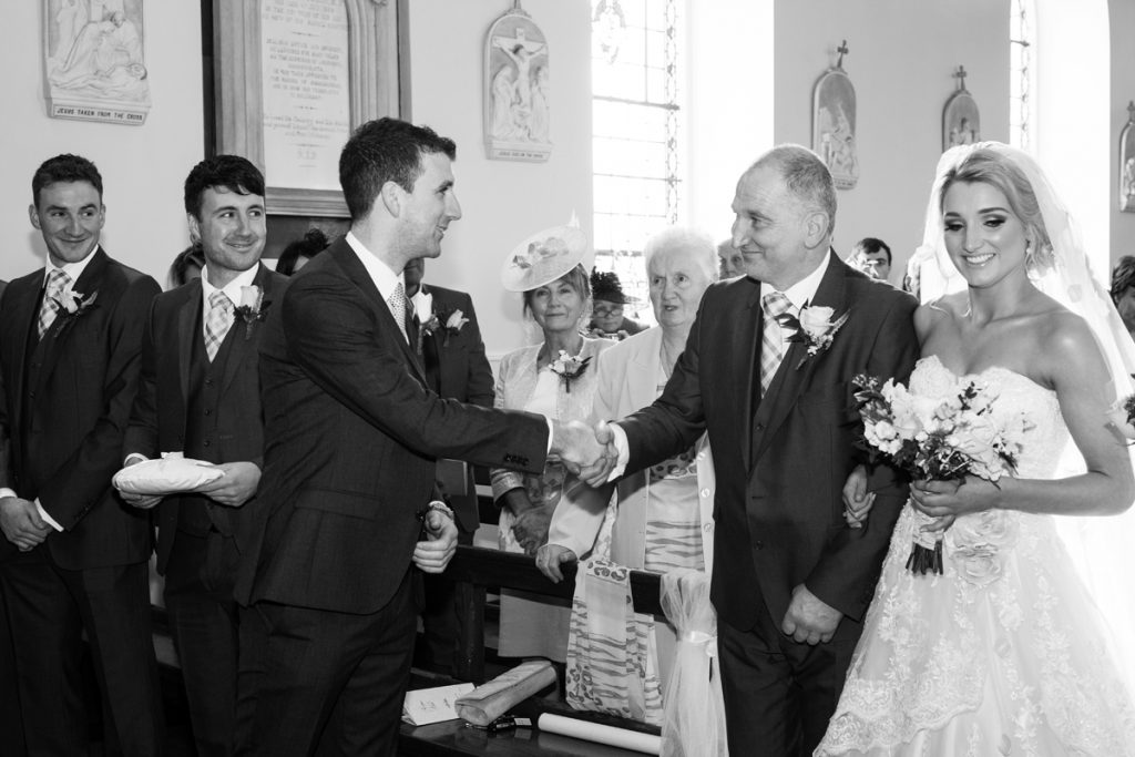 Picture of the father of the bride shaking hands with the groom on the altar