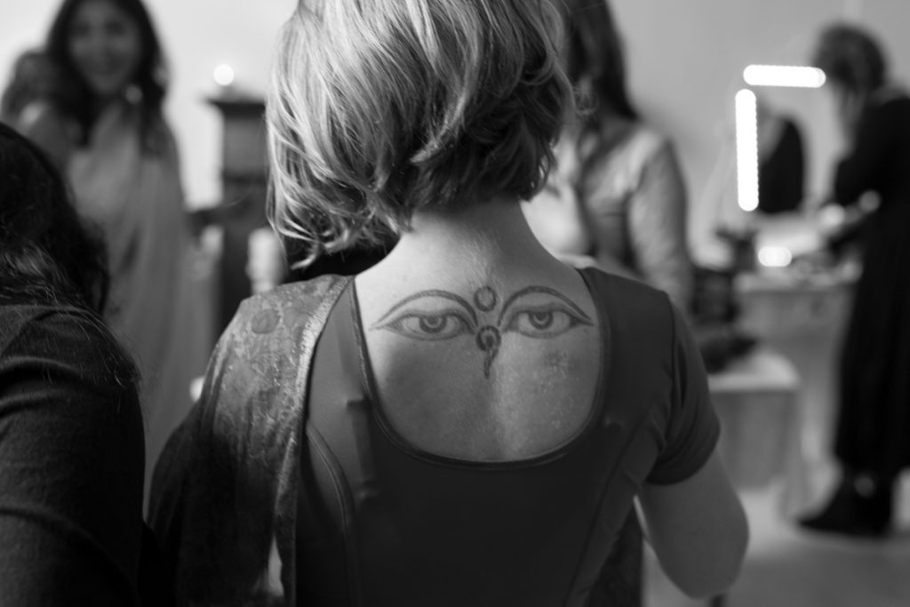 A picture of a woman's back that has a Nepali tattoo of the Buddha's eyes