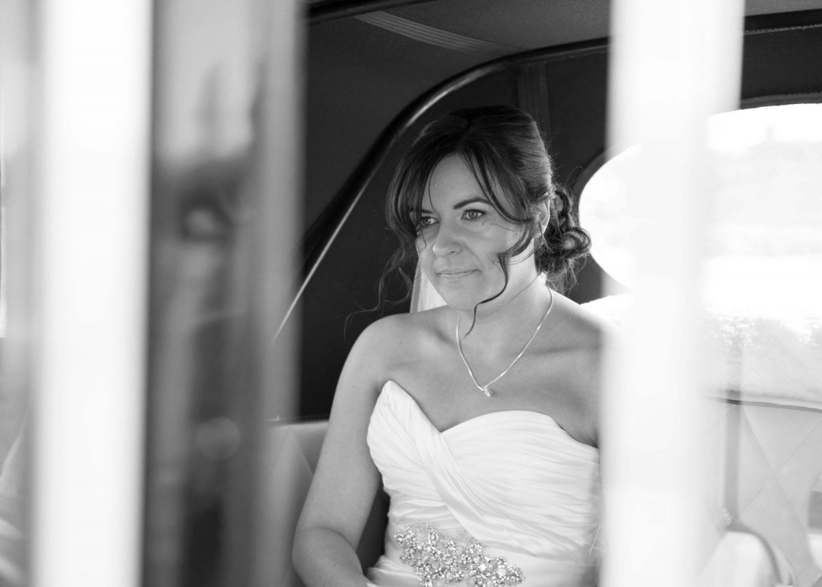 Black-and-white photo of a bride in the back of a car