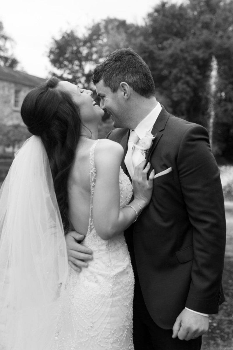Black-and-white photo of the bride with her head back laughing